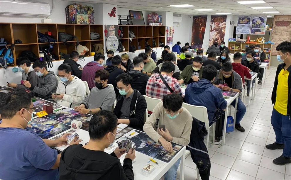 A wide shot of the Cat Footprints Zhongli store during the Skirmish event, with lines of players sitting at tables, playing games of Flesh and Blood